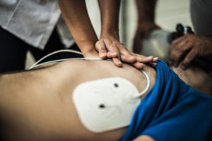 photo of man lying on the ground getting CPR and AED treatment