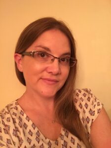 A woman with glasses is smiling for the camera.