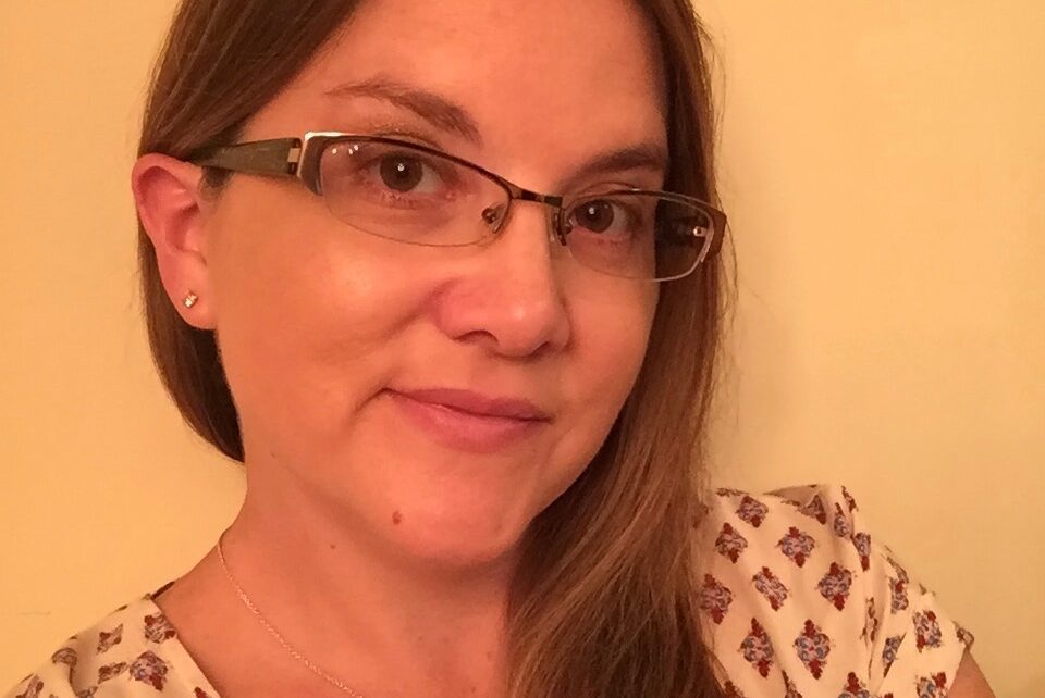 A woman with glasses is smiling for the camera.