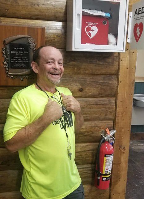 Man smiling near AED and fire extinguisher.
