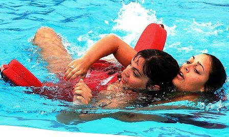 A woman in the water with her arms around another person.